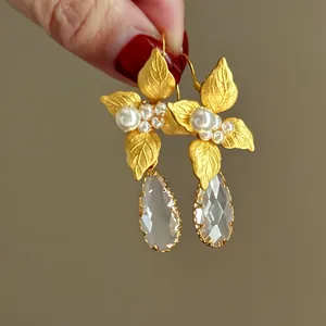 Dettaglio di eleganti orecchini a fiore dorati con perle e pendenti di cristallo