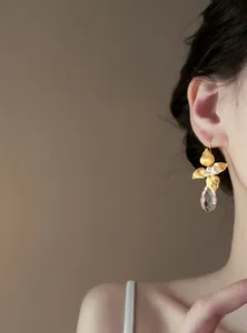 Vista dettagliata di eleganti orecchini a fiore in oro con perle e goccia di cristallo
