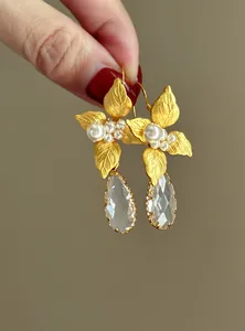 Primo piano di orecchini a foglia d'oro con perle e gocce di cristallo sfaccettato