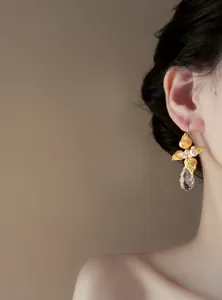 Primo piano di orecchini a foglia dorata con perle bianche e pendente in cristallo