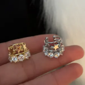 Vista dettagliata di eleganti ear cuff a stella in oro e argento con brillanti zirconi tondi