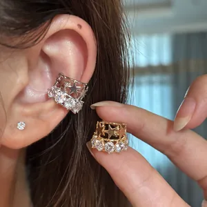 Dettaglio di eleganti ear cuff a stella in oro e argento con brillanti pietre di zirconia