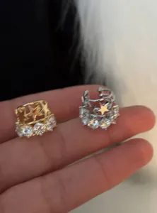 Vista dettagliata di eleganti ear cuff a stella in oro e argento con zirconi rotondi
