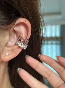 Primo piano di un ear cuff in argento con stelle e zirconi su un orecchio modella