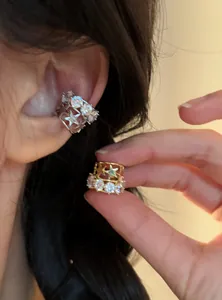 Dettaglio di orecchini a clip a stella in zircone argento e oro indossati e tenuti