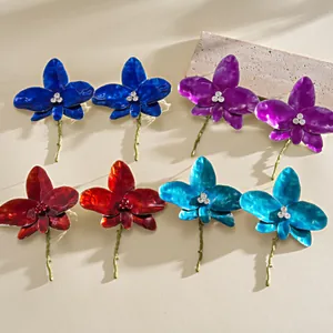 Detailed view of colorful enamel orchid flower earrings with rhinestone centers in four colors