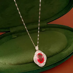 Close-up of an elegant oval red zircon pendant necklace in a luxury green velvet jewelry box