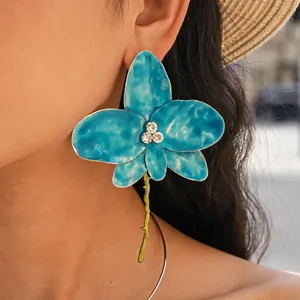 Macro shot showing the detail of blue enamel orchid flower earrings with rhinestone center.