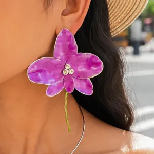 Elegant close-up of purple enamel orchid earrings with a silver choker necklace on model.