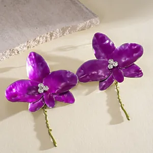 Detail view of purple enamel flower earrings with sparkling rhinestones and green stems