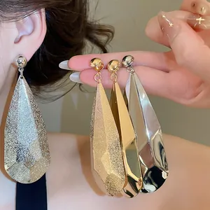 Vue détaillée de boucles d'oreilles gouttes métalliques plissées en or et en argent