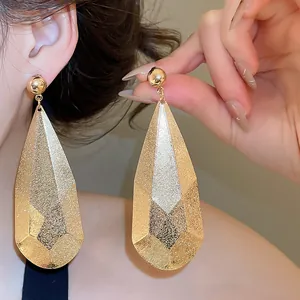 Gros plan de boucles d'oreilles en forme de goutte texturée dorée sur un mannequin