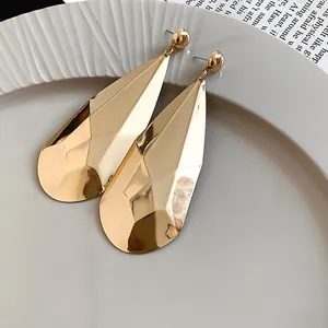 Gros plan détaillé de boucles d'oreilles dorées à facettes avec un fini métallique