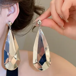Gros plan de boucles d'oreilles goutte d'eau en métal brillant avec un effet froissé unique