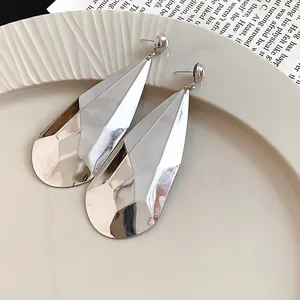 Gros plan sur des boucles d'oreilles pendantes argentées à facettes et effet froissé