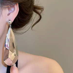 Gros plan de boucles d'oreilles pendantes en métal argenté facetté de grande taille