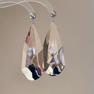 Gros plan de boucles d'oreilles pendantes argentées à facettes avec une finition brillante.