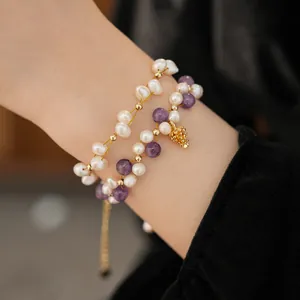 Detailed shot of double-layer freshwater pearl bracelet with amethyst and gold pinecone
