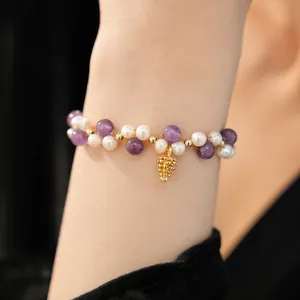 Close-up of elegant freshwater pearl and amethyst bracelet with a pinecone charm