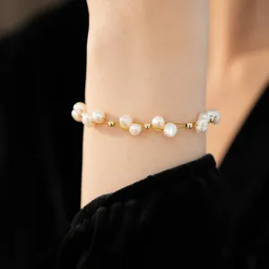 Detailed view of an 18k gold plated freshwater pearl beaded bracelet on a woman's wrist