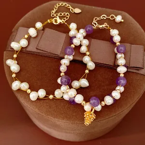 Close-up of freshwater pearl bracelet with amethyst beads and golden charm detail.