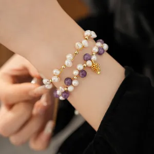 Detailed close-up of layered freshwater pearl and amethyst bracelets on wrist