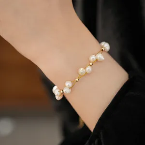 Close-up of a 18k gold plated freshwater pearl bracelet worn on a woman's wrist
