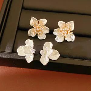 Close-up detail of elegant white enamel flower stud earrings with sparkling zircon accents