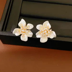 Elegant white flower stud earrings with small pearls and sparkling zircons on gold-tone base