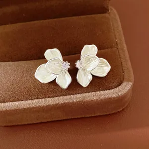 Elegant cream enamel flower stud earrings with sparkling zircon center on velvet box