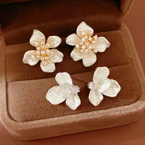 Detailed view of two pairs of elegant flower-shaped stud earrings in a jewelry box