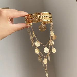 Détail d'un élégant bracelet de bras en métal doré avec des breloques de pièces et de longs glands