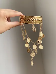 Gros plan détaillé d'un bracelet de bras doré avec pampilles de pièces et de chaînes