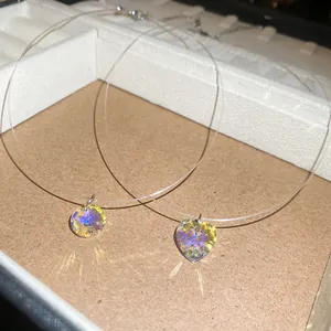 Vue détaillée des pendentifs en cristal irisé cœur et rond sur colliers à cordon invisible.