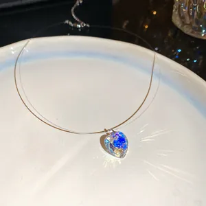 Gros plan d'un pendentif cœur en cristal scintillant sur une chaîne invisible