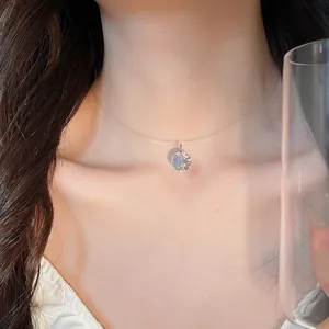 Gros plan d'un pendentif en cristal circulaire minimaliste sur un fil invisible de collier