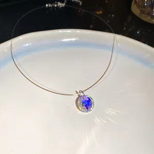 Gros plan d'un pendentif en cristal rond sur un collier en fil de pêche invisible.