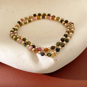 Detailed macro view of colorful faceted beads and a sparkling zircon charm on gold bracelet