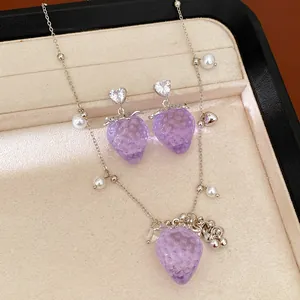 Vue macro détaillée des breloques fraises en résine violette et du collier de perles