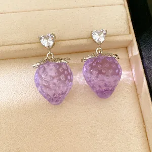 Vue détaillée de boucles d'oreilles fraise en résine violette avec cristal en cœur