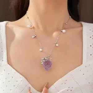 Détail d'un charmant collier avec pendentif fraise en résine violette et perles