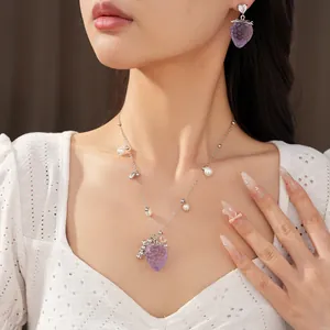 Vue détaillée du collier fraise en résine violette et des boucles d'oreilles perles