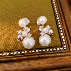 Elegant white pearl ear clips with sparkling zircon accents on green velvet background