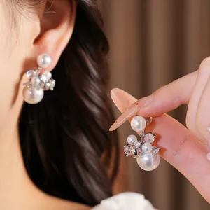 Close-up of elegant silver zircon pearl clip-on earrings worn on model's ear.