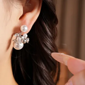 Close-up detail of elegant white pearl and sparkling zircon cluster earrings on ear