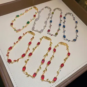 Elegant vine-shaped bracelets with colorful gemstones on a white jewelry tray.