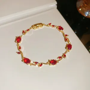 Detailed view of the gold-plated vine bracelet featuring ruby-red oval zircons.