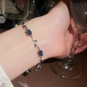 Detailed view of elegant vine-shaped silver bracelet with oval blue zircon gemstones