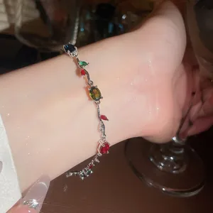 Close-up of a delicate vine-shaped bracelet with colorful zircon gemstones on a wrist.