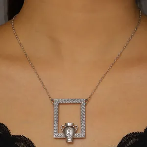 Close-up of artistic silver amphora pendant featuring floral relief and scroll textures